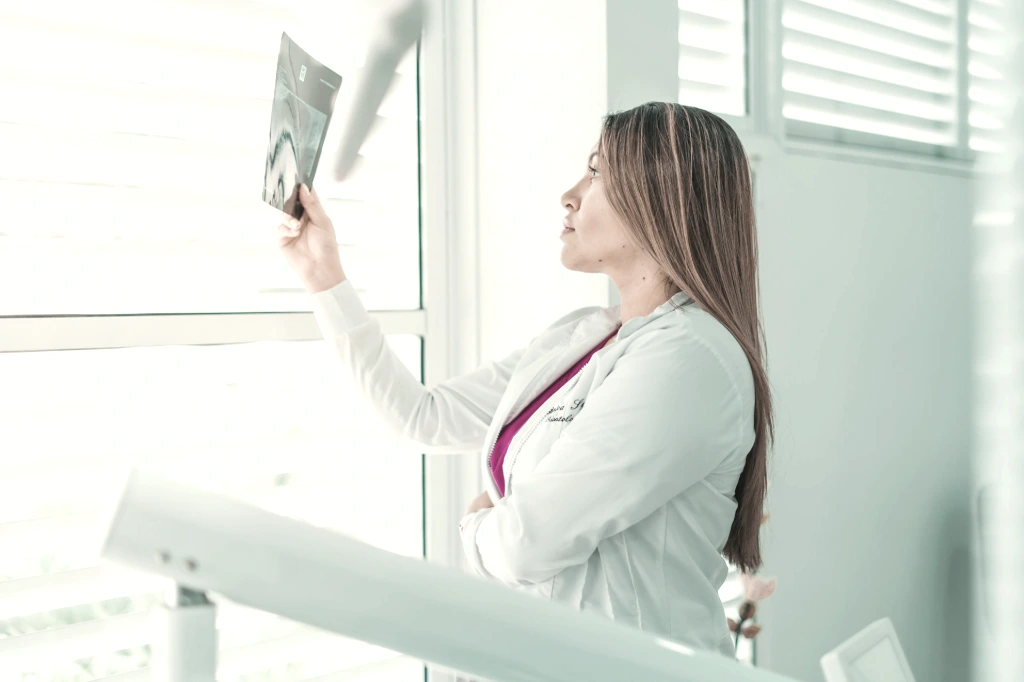 a woman in a white lab coat looking out a window
